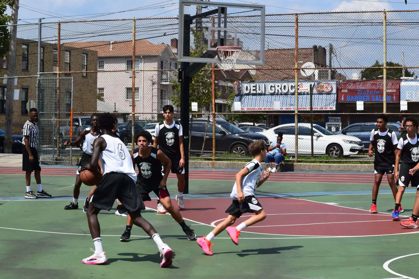 Youth players dribbling near hoop with deli backdrop